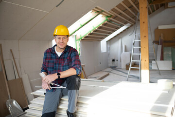 man on building site with yellow helmet works in drywall construction