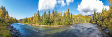 River Running Through The Boreal Forest Of Canada During Fall, Autumn Season With Spruce Trees Surrounding The Rushing Water Scenic View. 