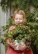 © malyutinaanna - Biophilic design, nature-inspired environment, biophilic interior. A beautiful girl is holding a flowerpot with a plant. Beautiful home interior, green areas and indoor plants.