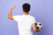 © luismolinero - Young Moroccan man isolated on purple background with soccer ball