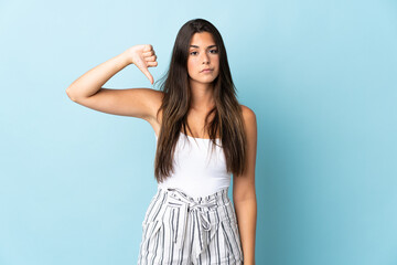 Young brazilian woman isolated on blue background showing thumb down with negative expression