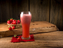 Strawberry Juice In The Glass On Wood With Basket Of Strawberries In The Background