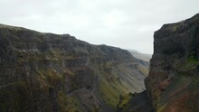 Deep Ravine With Steep Rocky Escarpments At Sides. People On Lookout Point On Edge Admiring Preserved Nature Treasure. Haifoss, Iceland