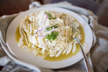 Plate with delicious green enchiladas on gray napkin