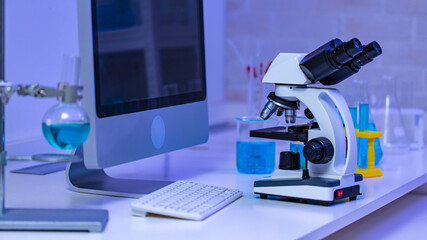 Sticker - Closeup studio shot of magnifier zooming lens microscope camera placing on working table in hospital laboratory full of glassware equipment test tube rack Erlenmeyer flask beaker and computer monitor