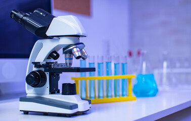 Wall Mural - Closeup studio shot of magnifier zooming lens microscope camera placing on working table in hospital laboratory full of glassware equipment test tube rack Erlenmeyer flask beaker and computer monitor