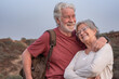 © luciano - Loving mature adult gray-haired Caucasian senior adult couple embracing on outdoor excursion. Two smiling relaxed seniors enjoying freedom and a healthy lifestyle in nature during their retirement