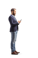 Wall Mural - Full length profile shot of a man in suit and jeans typing on a mobile phone