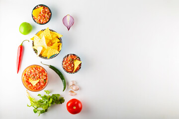 Wall Mural - Traditional mexican salsa sauce with ingredients on white background. Salsa sauce and nacho chips. Top view. Copy space