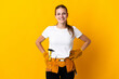 © luismolinero - Young electrician woman isolated on yellow background posing with arms at hip and smiling