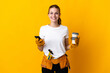 © luismolinero - Young electrician woman isolated on yellow background holding coffee to take away and a mobile