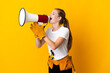 © luismolinero - Young electrician woman isolated on yellow background shouting through a megaphone
