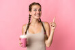 © luismolinero - Young woman with strawberry milkshake isolated on pink background pointing up a great idea