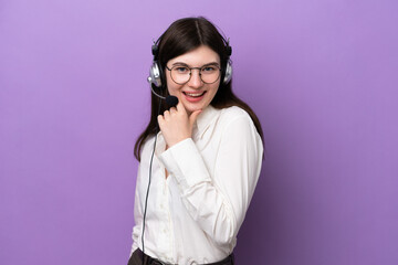 Wall Mural - Telemarketer Russian woman working with a headset isolated on purple background with glasses and smiling