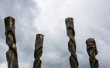 Old Tree Trunks, Artfully Twisted Like Screws, Tower Into The Cloudy Sky