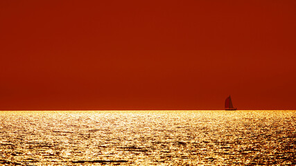 Wall Mural - Silhouette of a sailing boat in sunset sunrise time and ocean horizon.