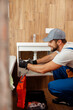 © Kostiantyn - Professional plumber, male worker in uniform looking busy while fixing sink in apartment