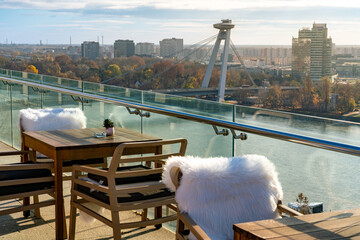 Café terrace with view of Danube river and iconic UFO bridge in Bratislava, empty with white seat furs