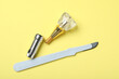 Parts of dental implant and medical knife on yellow background, flat lay
