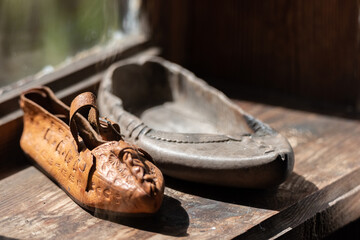 Leather boots from a previous era standing on a wooden board. The rustic atmosphere of an old shoemaker's shop.