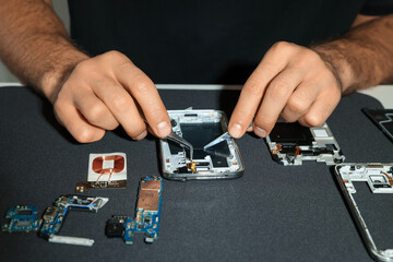 Wall Mural - Technician repairing broken smartphone at table, closeup