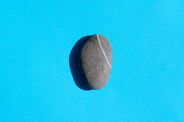 a stone with a hard shadow on a blue background