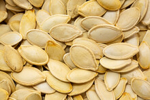 Background photo of pumpkin seed kernels. Close-up view of roasted pumpkin seeds. Shelled pumpkin seeds in the middle in selective focus.