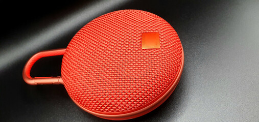 Red music speaker isolated closeup. Red speaker on a black background.