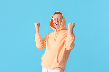 Canvas Print - Happy young guy in stylish hoodie on color background