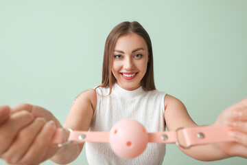 Wall Mural - Young woman with mouth gag on color background