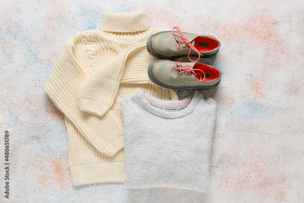 Warm children's sweaters and shoes on light background