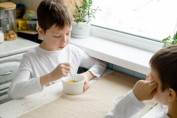 children eat colored cereals at the table, in the white kitchen. Breakfast for two boys. Breakfast cereals before school