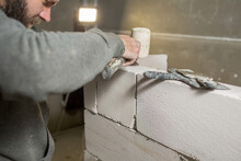 A Male Builder Puts A Wall Of Foam Concrete Blocks, The Process Of Installing The Block On The Wall Is Close-up..