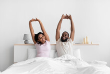 Smiling Young African American Male And Female Woke Up Stretching Body And Enjoy Morning On Comfort White Bed