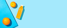 Detox Juice In A Plastic Bottle, Oranges On A Blue Background. Top View, Flat Lay. Banner.
