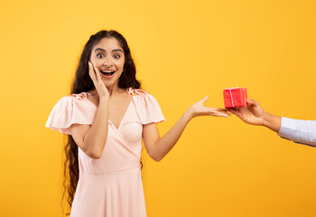 Presents delivery, holiday celebration concept. Hand holding and giving gift box to surprised excited indian woman