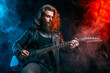 © zamuruev - Guitar player. Rockstar bearded man plays on guitar isolated on smoke background. Studio shot
