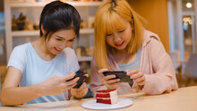 Cheerful Young Asia Friend Using Phone Taking A Photograph Food And Cake At Coffee Shop. Two Joyful Attractive Asian Lady Together At Restaurant Or Cafe. Holiday Activity, Or Modern Lifestyle Concept.