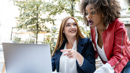 business women working outdoor in remote with laptop, focus on red head professional woman pointing at a document on screen device