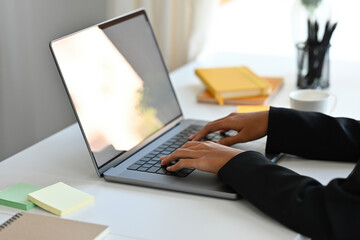 Poster - Close-up image of a businesswoman's hand typing on a white blank screen computer laptop at the modern working desk.