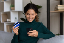 Happy Millennial Attractive Woman Holding Banking Card And Cellphone In Hands, Feeling Satisfied With Secure Internet Payment, Transferring Money Or Paying For Services, Online Shopping Concept.