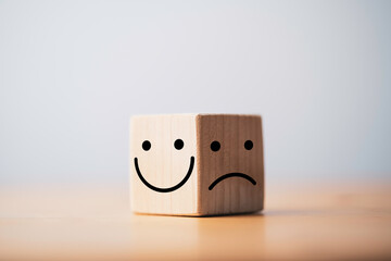 Wall Mural - Smile face in bright side and sad face in dark side on wooden block cube for positive mindset selection concept.