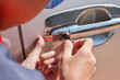 Close-up Of Person's Young Man Locksmith Hand Opening Bronze Car Door With Lock picker. Locksmith door opening device.