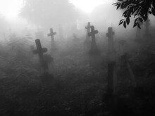 Dark Ancient Cemetery In The Fog. Crosses And Graves In The Old Abandoned Cemetery. Place Of Burial. Black White Photo.	