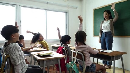 Wall Mural - Group of diverse elementary school kids with notebooks sitting in classroom and raise arm up to answer teacher question. Education, elementary school, learning, Back to school concept 