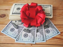 stack of usa dollars and bow on wooden background, money gift concept