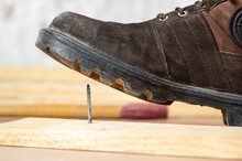 Close-up Of Man's Foot Stepping Over There Nail Inserted In Wooden Plank.Home Safety Concept