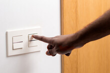Close Up Of Man Hand Turning On The Light With A Wall Switch At Home