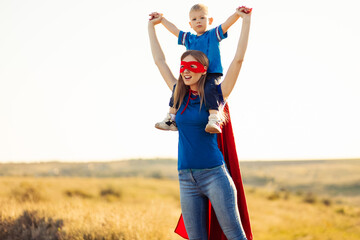 Mom and son play superheroes, Happy mom holds a small child in her arms, simulate flight, pretend to be real superheroes