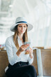 © GRAFStock - Casual young woman using her cell phone while waiting to board a plane at the departure gate